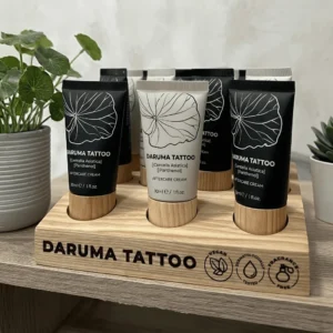 Daruma Tattoo vegan aftercare cream displayed on wooden stand with black and ashen tubes
